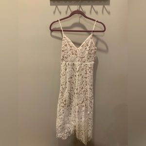 White lace dress with handkerchief hem and adjustable straps.